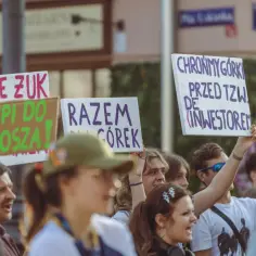Ludzie na proteście trzymają transparenty: "Panie Zuk zpi do kosza!", "Razem dla Górek", "Chrońmy Górki przed tzw. dezinwestorem". Widać ich zaangażowanie i partycypację w obronie przyrody.