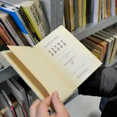Otwarta książka "Lalka" Bolesława Prusa, idealna lektura dla klasy 6. Obok półki z innymi lekturami.
