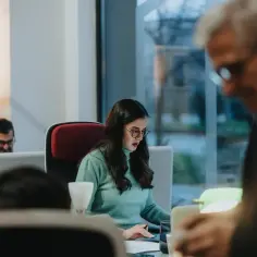 Kobieta w okularach skupiona na pracy przy biurku, przykład etyki zawodowej w nowoczesnym biurze.