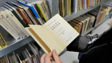 Otwarta książka "Lalka" Bolesława Prusa, idealna lektura dla klasy 6. Obok półki z innymi lekturami.